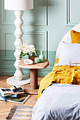 Bedside table and white floor lamp against mint green wall in bedroom