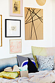 Framed picture and DIY cardboard pinboard above sofa with scatter cushions