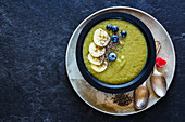 Detox spring green smoothie bowl served with banana, chia seeds and blueberries