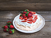 Rustic Pavlova cake with fresh strawberries and whipped cream