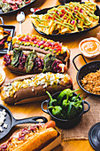 Viele verschiedene Snacks und Hot Dogs mit Saucen und Gewürzen auf Holztisch
