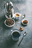 Kaffeebohnen und Kaffeepulver sowie schwarzer Kaffee und Espresso in Tassen