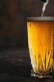 Pouring beer into a glass on dark background