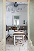 Transparent chairs around table below designer ceiling lamp in kitchen