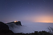 Night sky above clouds and Buddhist mountain