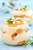 Closeup of bowls with apricot tiramisu on a table in pastel colors with jasmine flowers
