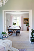 View through open sliding door into dining room with long table and various chairs