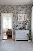 White-painted wooden chest of drawers against blue-and-white wallpaper