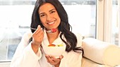 Woman eating bowl of fruit