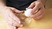 Man cracking egg with shaking hand