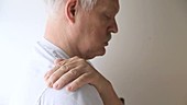 Man rubbing painful shoulder