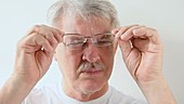 Man taking off glasses and wiping them