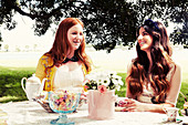 Two young women sitting at a festively laid garden table