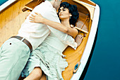 Dunkelhaarige Frau und Mann liegen in einem Boot