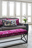 Grey sofa with colourful scatter cushions and bench with floral seat cushion