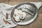 Cinnamon rolls with cream-cheese icing and cinnamon sticks on a silver dish