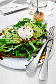 Avacado and poached eggs on rocket and toast with sprikled sesame seeds