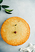 Cherry pie topped with a cherry on grey background