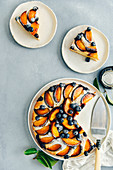 Peach cake with bluberries with a cake server on the side sliced