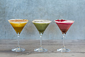 Dreierlei Latte in Cocktailgläsern: Kurkuma-Latte, Matcha-Latte und Rote-Bete-Latte