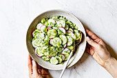 Creamy Cucumber Salad in a ceramic bowl on a marble work surface