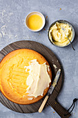 A round homemade orange cake partially spread with butter icing