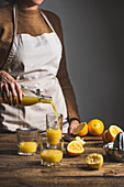 Frau giesst Orangensaft aus Bügelflasche in Gläser
