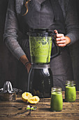 A woman preparing a green green smoothie in a blender