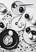 Black, white and speckled eggs on a table with black-and-white crockery