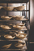 Bread dough in proving baskets on a shelf in a bakery