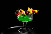 A green drink with an exotic fruit skewer
