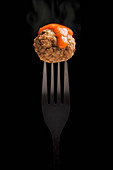 Fork with delicious meatball and tomato sauce