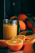 Frische Orangen und Glas mit Orangensaft