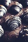 Black croissants with active charcoal powder on a baking tray
