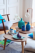 Aquafarbene Vasen, Tischleuchte und fischförmiger Teller auf Beistelltischchen