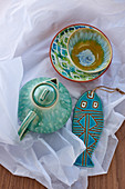 Ceramic teapot, dishes and fish ornaments glazed in shades of turquoise