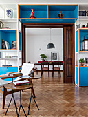Blue and white shelving surrounding doorway with sliding wooden door and set of side tables in foreground