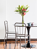 Schwarzer, runder Tisch mit Blumenstrauß und Vintage Metallstühle