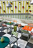 Chairs and bistro tables in restaurant on roof terrace with potted plants on wall
