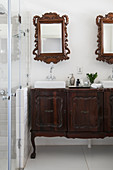 Twin countertop sinks on antique base unit below two mirrored cabinets incorporating antique mirror frames