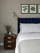 Double bed with deep-blue headboard, wall-mounted lamp and bedside cabinet in bedroom