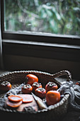 Persimmons on a rustic wood table top in a woven wicker basket