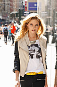 Junge blonde Frau in T-Shirt, Bikerjacke und schwarzer Hose