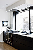 Black kitchenette with gas stove under the panoramic window