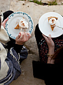 Two women sitting on stone steps eating slices of pumpkin pie
