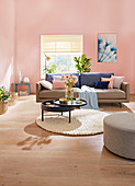 Ledersofa und runder, schwenkbarer Couchtisch im Wohnzimmer mit rosa Wänden