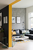 Black leather couch and grey wall in open-plan interior