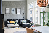 Black leather couch and coffee table next to window and grey mottled wall in open-plan interior
