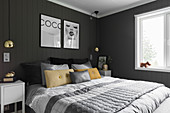 Double bed and bedside cabinets against charcoal wall in bedroom