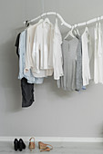 Kleidungsstücke hängen an DIY-Kleiderstange aus weiß gestrichenem Ast
